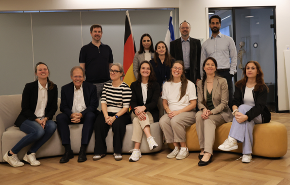 Foto: Gruppenfoto einer Delegation von Wissenschaftlerinnen und Wissenschaftlern. Im Hintergrund sind die Deutsche und die Israelische Flagge zu sehen.